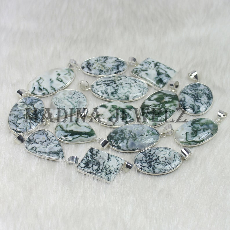 May include: A collection of gemstone pendants with silver-colored settings. The pendants feature a white and green patterned stone. Various shapes are visible, including oval, round, and rectangular. The text "MADINA JEWELZ" is visible on the image.