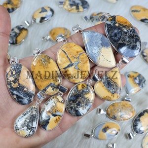 May include: A collection of gemstone pendants in various shapes, including oval and teardrop. The pendants feature a mix of tan, gray, and black patterns, set in silver-colored metal. The text "MADINA JEWELZ" is visible on some pendants.