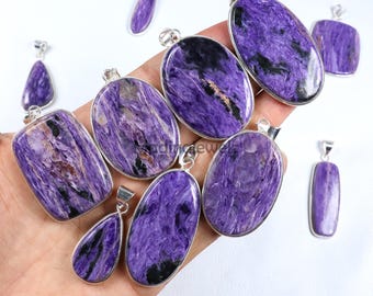 May include: A collection of purple charoite pendants with silver-colored settings. The pendants vary in shape, including oval, rectangular, and teardrop designs. The charoite stones display a swirling pattern of purple and black hues.