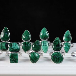 Pu&ograve; includere: Una collezione di nove anelli d'argento con pietre preziose di malachite verde. Gli anelli presentano una variet&agrave; di forme e dimensioni di malachite, tra cui forme a goccia e quadrate.
