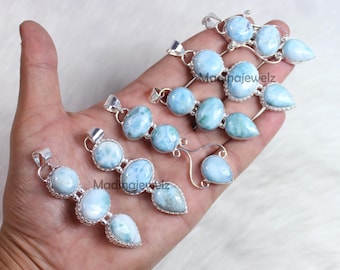 Könnte beinhalten: Mehrere silberne Anhänger mit hellblauen Larimar-Steinen werden gezeigt. Die Anhänger haben verschiedene Formen, darunter oval und tropfenförmig, und sind in Silber gefasst. Das Bild ist aus der Nähe aufgenommen und zeigt den Schmuck.