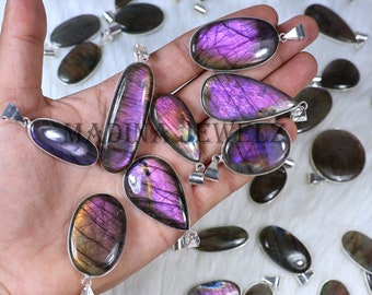 Può includere: Una collezione di ciondoli in labradorite iridescente con anelli in argento. Le pietre sono di varie tonalità di viola, grigio e nero con un effetto scintillante.