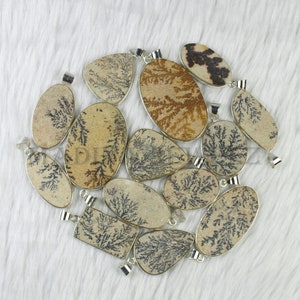 May include: A collection of 12 dendritic agate pendants with silver bail settings. The pendants are various shapes and sizes, with a natural brown and black dendritic pattern.