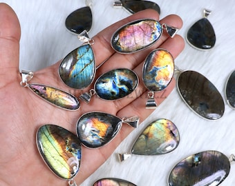 Può includere: Una collezione di 14 ciondoli in labradorite iridescente con montature in argento. I ciondoli sono di varie forme, tra cui a goccia e ovale. Le pietre mostrano una gamma di colori, tra cui blu, verde, oro e viola.
