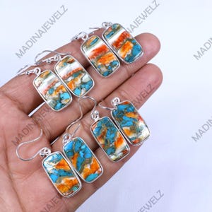 Puede incluir: Un conjunto de seis pendientes de plata con detalles de piedras turquesa, naranja y blanca. Las piedras son rectangulares y tienen un patrón único de mármol.