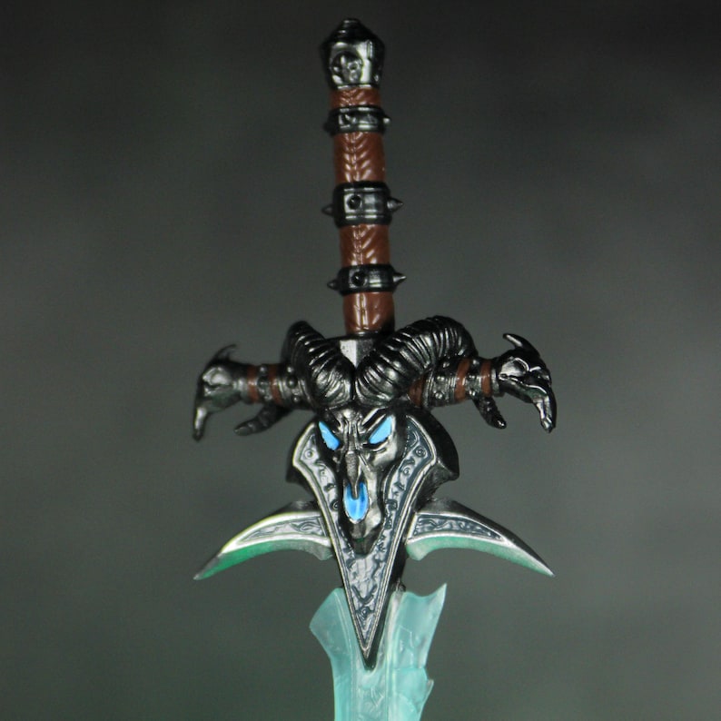 May include: A black and silver sword with a skull-like design and blue glowing eyes. The sword has a brown leather handle with metal accents.