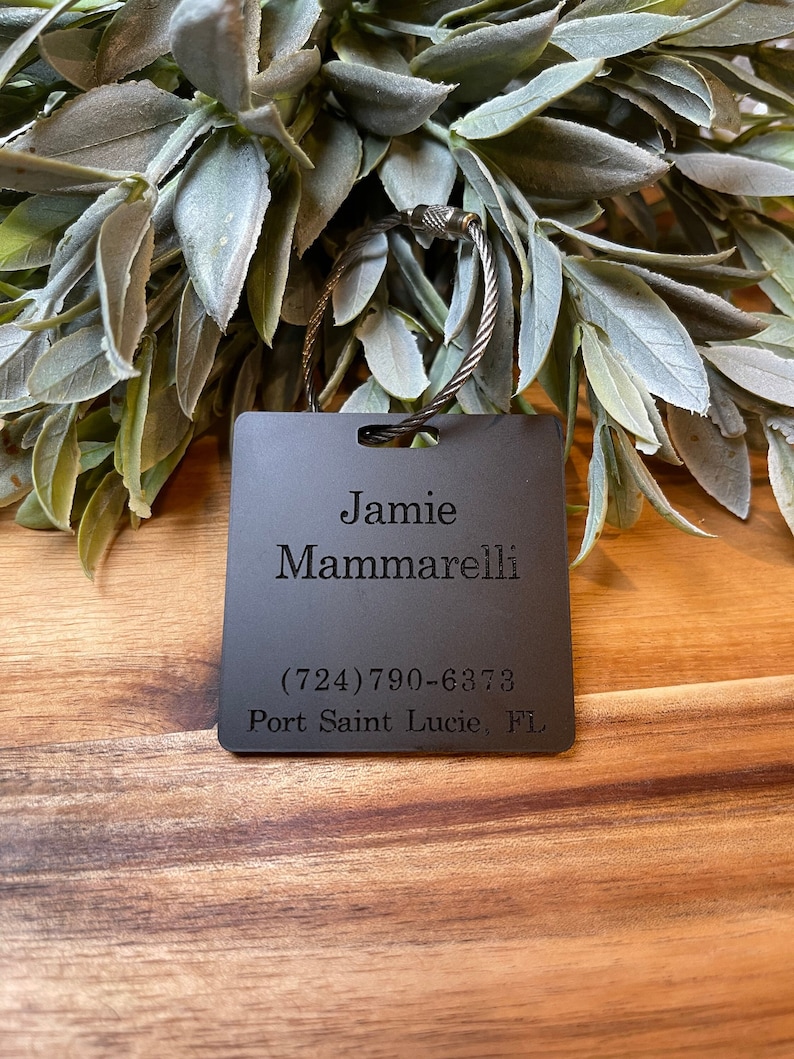 Puede incluir: Llavero de metal negro con texto grabado: "Jamie Mammarelli (724) 790-6873 Port Saint Lucie, FL"
