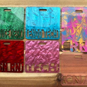 May include: Six different coloured plastic name tags with various job titles cut out. The colours are green, blue, pink, red, yellow, and brown. The titles are "Service Desk", "Endo Tech", "RN", "BSN RN", "Tech", and "CNA".
