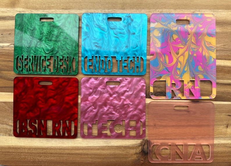 May include: Six different coloured plastic name tags with various job titles cut out. The colours are green, blue, pink, red, yellow, and brown. The titles are "Service Desk", "Endo Tech", "RN", "BSN RN", "Tech", and "CNA".