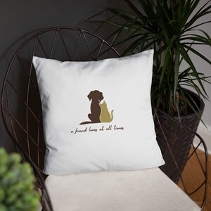 May include: White throw pillow with a brown dog and a yellow cat silhouette. The text "a friend loves at all times" is printed below the silhouettes.