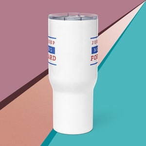 May include: White tumbler with a clear lid. The tumbler has the words "KEEP MOVING FORWARD" printed in red and blue. The tumbler is cylindrical and has a tapered base. The background is a mix of pink, teal, and blue.