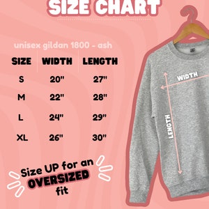 May include: Size chart for a unisex Gildan 1800 ash sweatshirt. The chart shows the width and length measurements in inches for sizes S, M, L, and XL. The text "Size UP for an OVERSIZED fit" is also included.