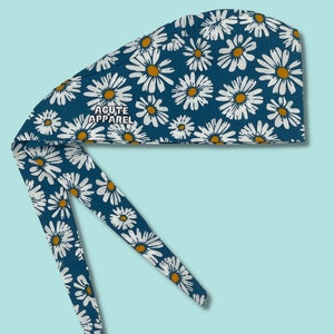 Puede incluir: Un gorro quirúrgico azul con estampado de margaritas blancas y el texto "ACUTE APPAREL" en blanco.