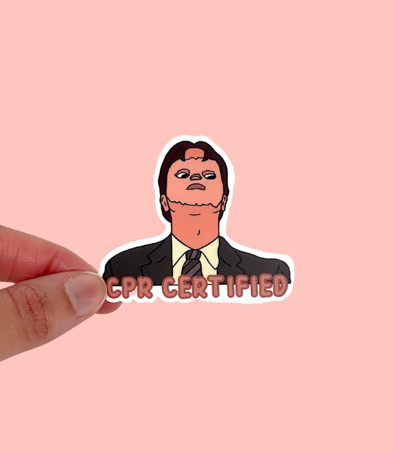 May include: A sticker featuring a cartoon illustration of a man in a suit with the text "CPR CERTIFIED". The man has a surprised expression and a red face. The sticker is held against a pink background.
