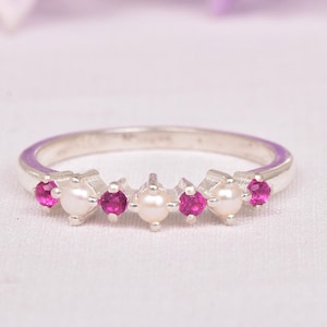 Może przedstawiać: Srebrny pierścionek z rzędem naprzemiennie różowych kamieni szlachetnych i białych pereł.