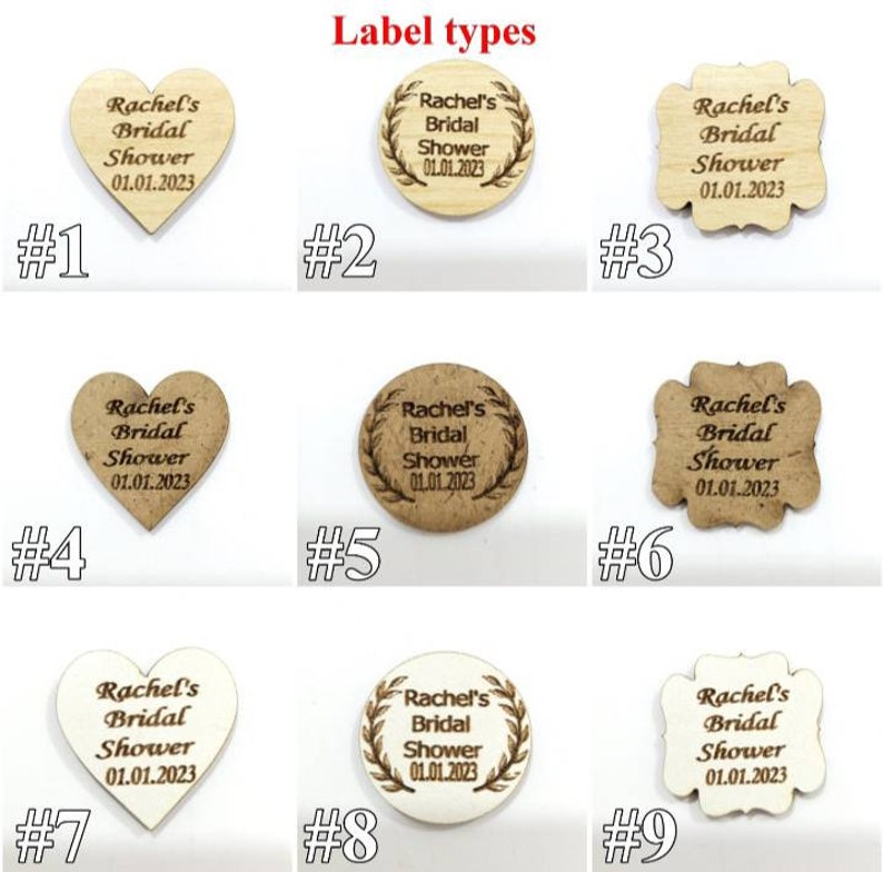 K&ouml;nnte beinhalten: Neun Holzanh&auml;nger in Herz-, Kreis- und Wellenformen, jeweils graviert mit dem Text Rachel's Bridal Shower 01.01.2023. Die Anh&auml;nger sind in einem Raster angeordnet und von eins bis neun nummeriert, wobei verschiedene Holzt&ouml;ne und Texturen zu sehen sind.