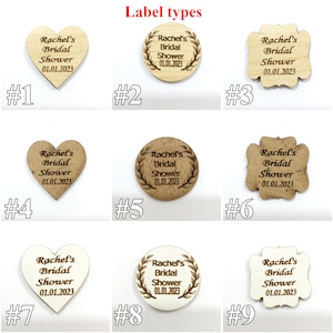 May include: Nine wooden labels in heart, circular, and scalloped shapes, labeled #1 through #9. Each features the engraved text Rachel's Bridal Shower 01.01.2023. The labels vary in wood tone from light to dark, with some circular designs featuring a leaf border.