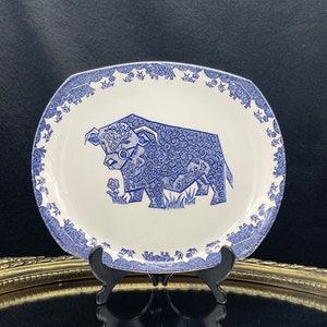 May include: A white ceramic plate with a blue and white design of a bull. The bull is surrounded by a border of blue flowers and leaves.