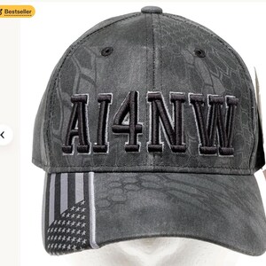 May include: A gray baseball cap with the text "AI4NW" embroidered in black. The cap features a camouflage pattern and a design with the American flag on the brim. A "Bestseller" badge is in the top left corner.