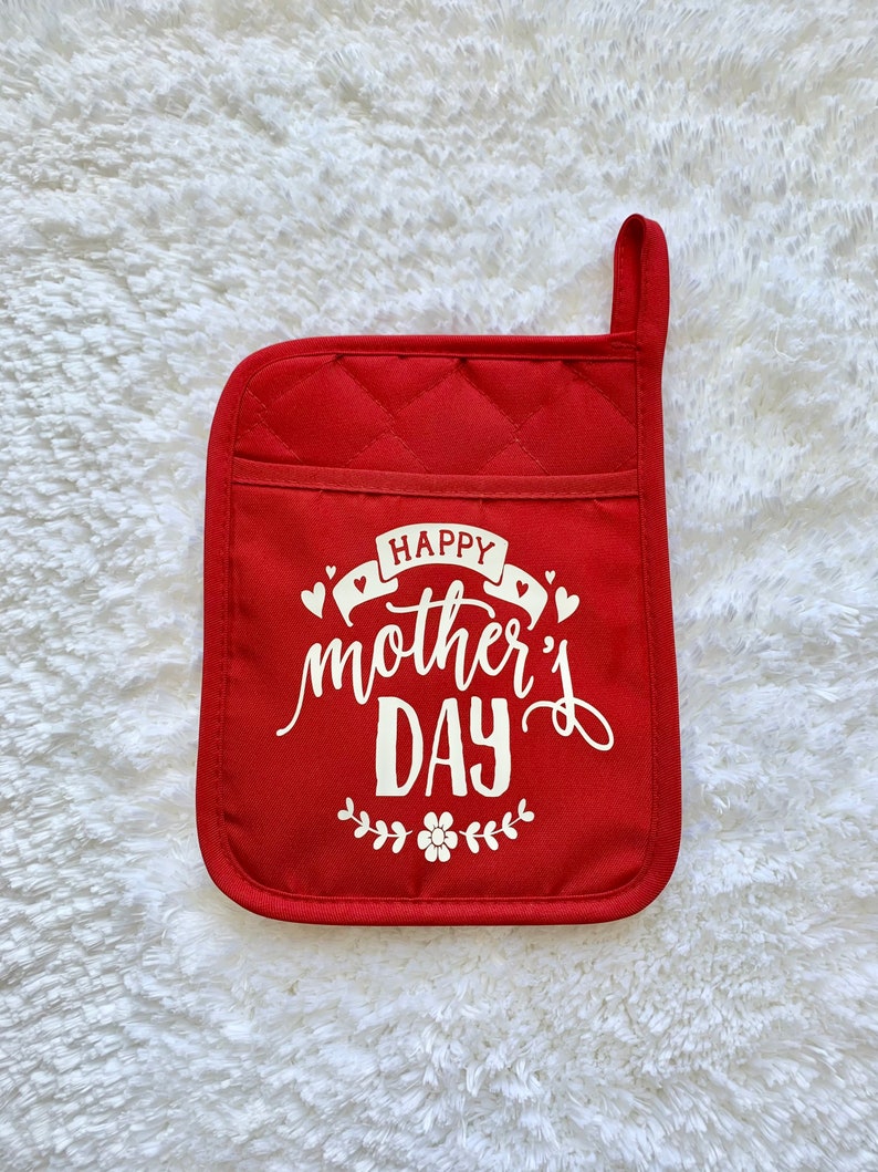 May include: Red quilted pot holder with white text that reads "Happy Mother's Day" with a small floral design.