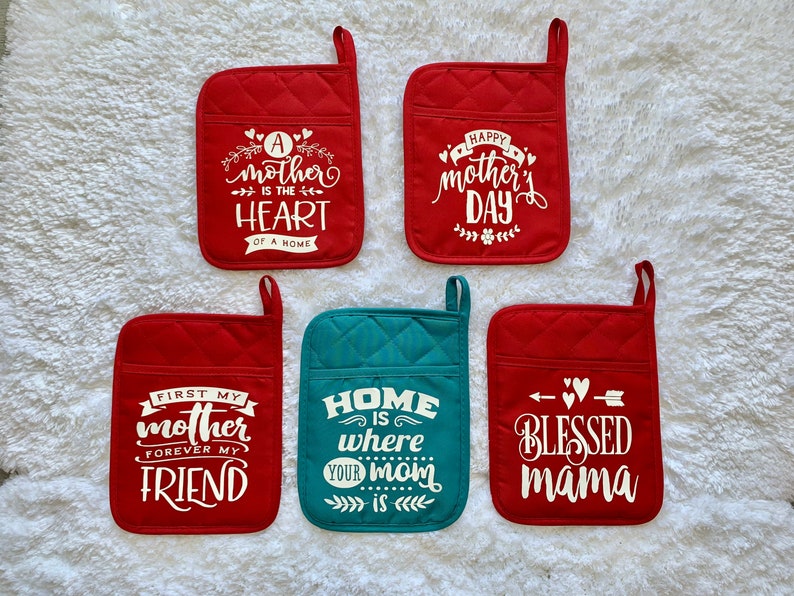 May include: Set of six red and teal pot holders with white text. The text on the pot holders reads: "A mother is the heart of a home", "Happy Mother's Day", "First my mother forever my friend", "Home is where your mom is", and "Blessed mama".