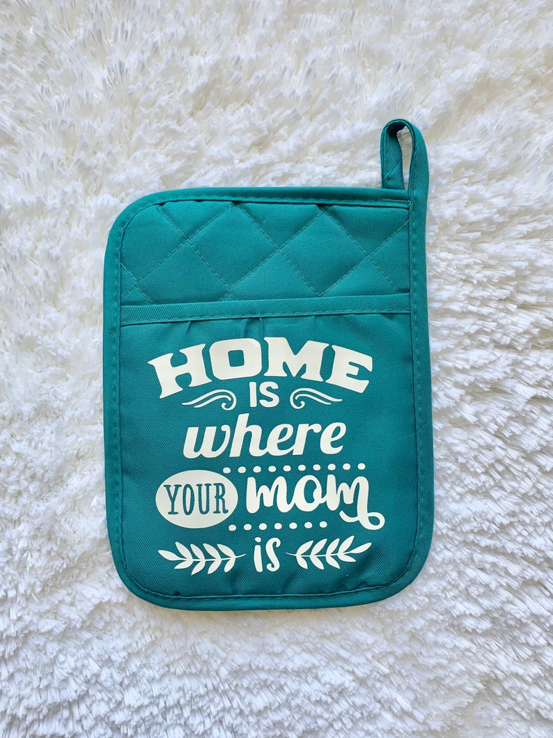 May include: Teal quilted pot holder with the text "Home is where your mom is" in white.