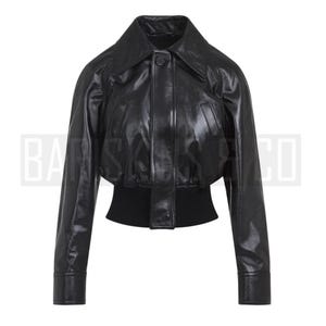 May include: A black leather jacket with a wide collar and a button closure. The jacket has long sleeves and a fitted waist with a ribbed knit band. The jacket is a cropped style.
