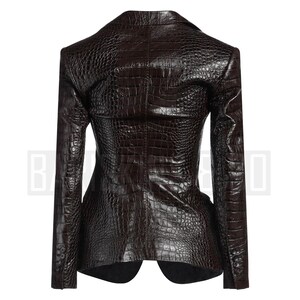 May include: A dark brown blazer with a textured, crocodile-skin pattern. The tailored jacket features a notched lapel, long sleeves, and button details. The back view of the blazer is shown, highlighting the structured design and fit.