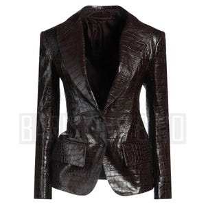 May include: A dark brown blazer with a crocodile skin texture. The blazer has a notched lapel, two front pockets, and a single-button closure. The jacket is tailored with a fitted silhouette.