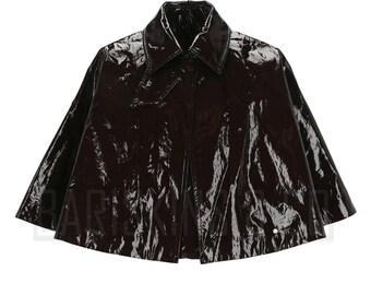 May include: A glossy, dark brown cape with a pointed collar and button closure. The cape has a shiny, patent leather-like appearance and a classic design. The garment is a stylish outerwear piece.