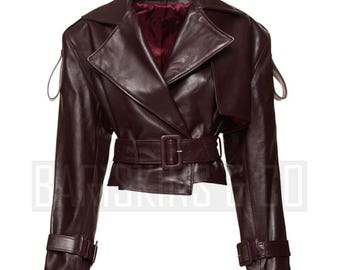 May include: A burgundy leather jacket with a belted waist and a slightly oversized fit. The jacket has a collar and long sleeves with a button closure.