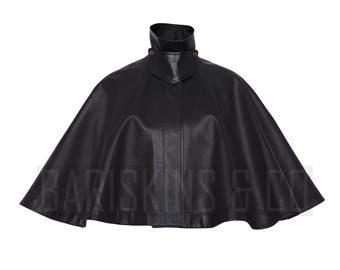 May include: A black leather cape with a high collar and two button closures. The cape has a wide, flowing design and is made of a smooth, shiny material. The text "BARISKINS & CO" is visible at the bottom.