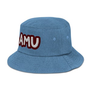 以下が含まれることがあります： 白い縁取りのある赤い文字で「AMU」と刺繍された、青いデニムのバケットハットです。