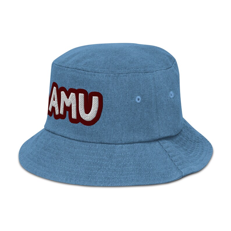 以下が含まれることがあります： 白い縁取りのある赤い文字で「AMU」と刺繍された、青いデニムのバケットハットです。