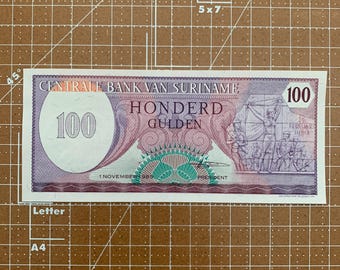 Stary surinamski banknot 100 guldenów - kolekcjonerska waluta z 1989 r., pięknie zaprojektowany, przedstawiający historię Surinamu.