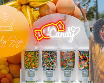 Può includere: Un espositore bianco con otto distributori di caramelle in vetro trasparente riempiti di palline di gomma colorate. Un'insegna al neon riporta la scritta Candy con un grafico di una caramella. Un grande palloncino arancione mostra il testo Candy Sign e una sagoma in cartone di una persona si trova accanto all'unità, circondata da palloncini dorati e arancioni.
