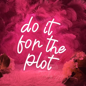 May include: A neon sign with the phrase "do it for the plot" in a cursive font. The sign is white and set against a pink background with a fluffy texture. White flowers and foliage are at the bottom.