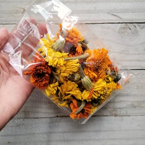 Puede incluir: Una bolsa de pl&aacute;stico llena de flores de cal&eacute;ndula secas de color naranja y amarillo.