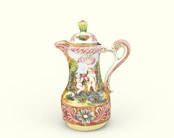 May include: A decorative ceramic pitcher with a lid, featuring a detailed painted scene of cherubs in a garden setting. The pitcher has a curved handle and spout, with a floral design at the base and on the lid. The color palette includes pink, green, and gold accents.