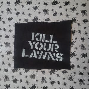 Peut inclure: Un patch noir avec les mots "KILL YOUR LAWNS" en lettres blanches. Le fond est un motif gris clair de divers insectes noirs, dont des mouches, des araignées et des coléoptères. Le patch est carré.
