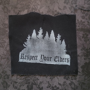 May include: Black fabric patch with a white silhouette of a forest and the text "Respect Your Elders" in white.