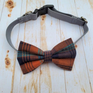 May include: A gray dog collar with a plaid bow tie in shades of orange, blue, and black.