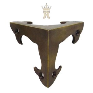 Puede incluir: Un soporte de esquina de color bronce con un dise&ntilde;o decorativo. El soporte tiene forma triangular con bordes curvos y tres agujeros para tornillos. Est&aacute; dise&ntilde;ado para reforzar esquinas.