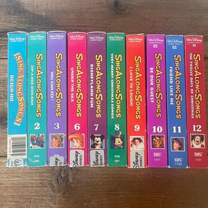 May include: A set of 12 VHS tapes featuring Disney's Sing Along Songs. The tapes are arranged in order from 1 to 12, with each tape featuring a different song and characters. The tapes are all in their original packaging and are in good condition.
