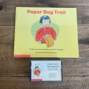 May include: A children's book titled "Paper Bag Trail" by Anne Schreiber and Arbo Doughty, with illustrations by Ward Schumaker, and a matching cassette tape. The book cover is yellow with a cartoon illustration. The cassette tape is in a clear case.