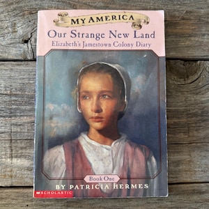 May include: A book titled "Our Strange New Land" from the "My America" series. The cover features a portrait of a young girl in a white bonnet and a pink vest. The author's name, Patricia Hermes, is visible.