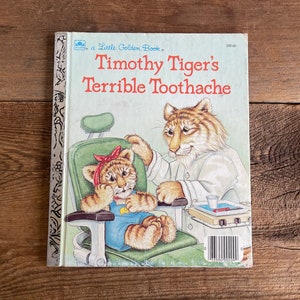 May include: A Little Golden Book titled "Timothy Tiger's Terrible Toothache" featuring an illustration of a tiger dentist examining a young tiger patient in a dentist's chair.