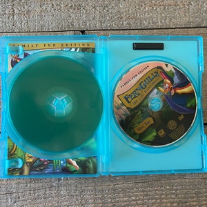 Op de afbeelding: Een blauwe DVD-doos met een afbeelding van een cartoonvogel op de voorkant. De doos is open en de DVD is zichtbaar. De DVD is gelabeld met "FernGully: The Last Rainforest" en "Disc Two".