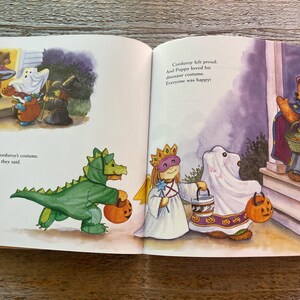 May include: A children's book illustration showing a group of characters dressed in costumes for Halloween. The characters include a dinosaur, a ghost, a princess, and a bear. The text in the image reads "Everybody loved Corduroy's costume. "What a creative idea!" they said. Corduroy felt proud. And Puppy loved his dinosaur costume. Everyone was happy!"