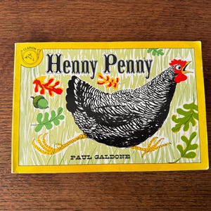 以下が含まれることがあります： 「Henny Penny」というタイトルの子供向けの本で、ニワトリの白黒イラストが描かれています。表紙は黄色の縁取りで、作者の名前、ポール・ガルドーネが記載されています。